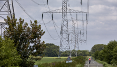 hoogspanningsmast met een weg erlangs waar fietsers fietsen