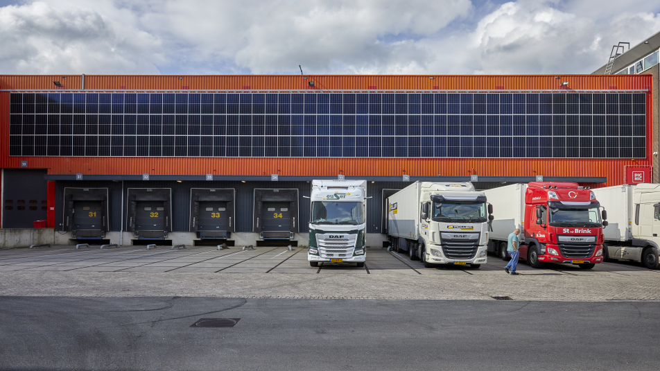 bedrijf met zonnepanelen op de gevel en vrachtwagens voor het pand