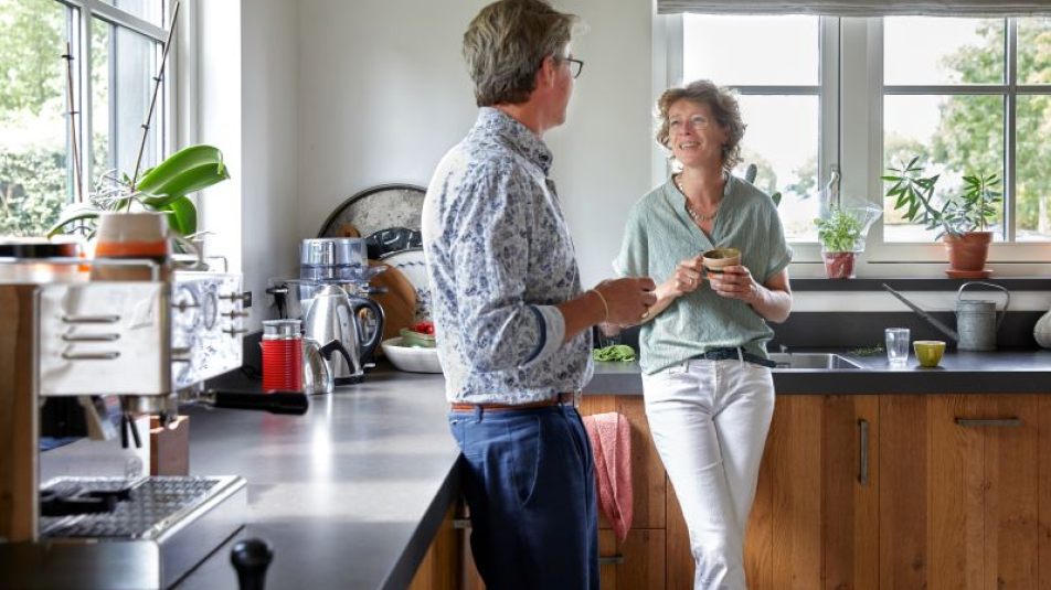 Particuliere woningeigenaren met koffie in de keuken van een comfortabel huis