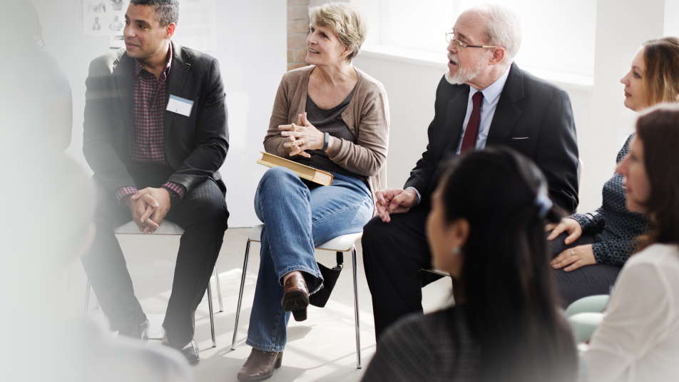 Groep mensen zit bij een bijeenkomst n een kring in een zakelijke setting