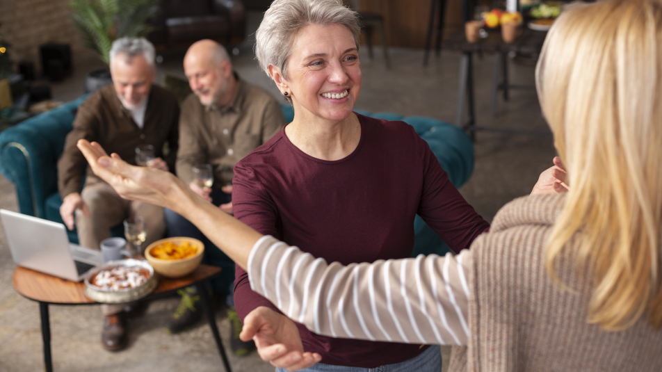 Mensen in woonkamer, een oudere dame begroet een nieuwkomer